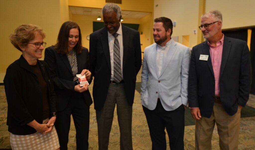 Five individuals, two women and three men, standing and looking at a bag of ready-to-use therapeutic food.