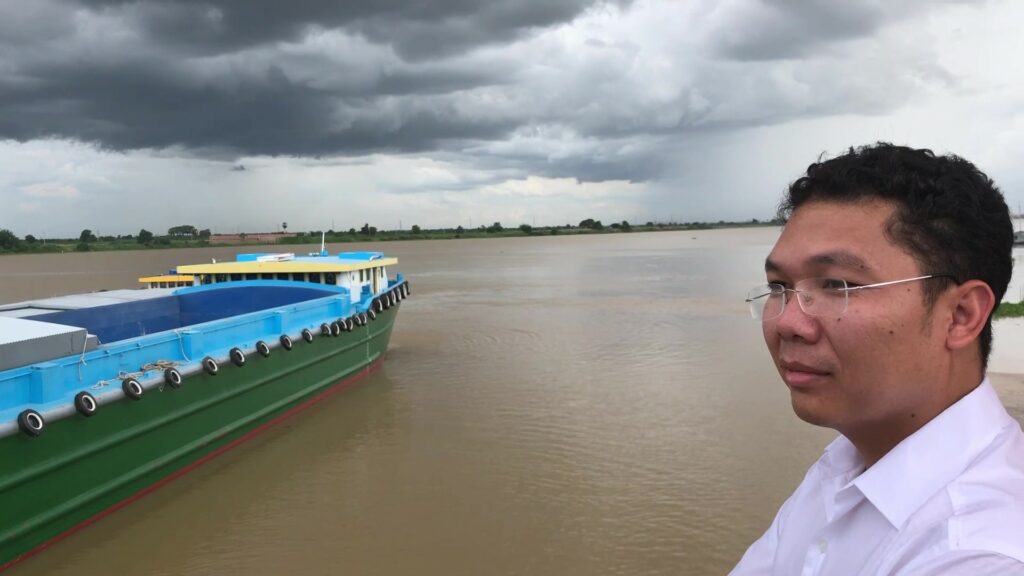 A Cambodian man named Rady Chea standing in front of a body of water with a boat on the left.