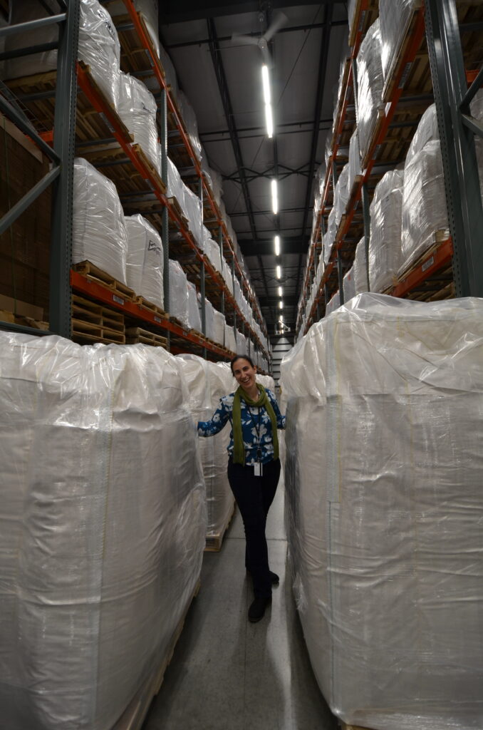 A woman in a warehouse standing between two bulk orders of U.S. soy flour.