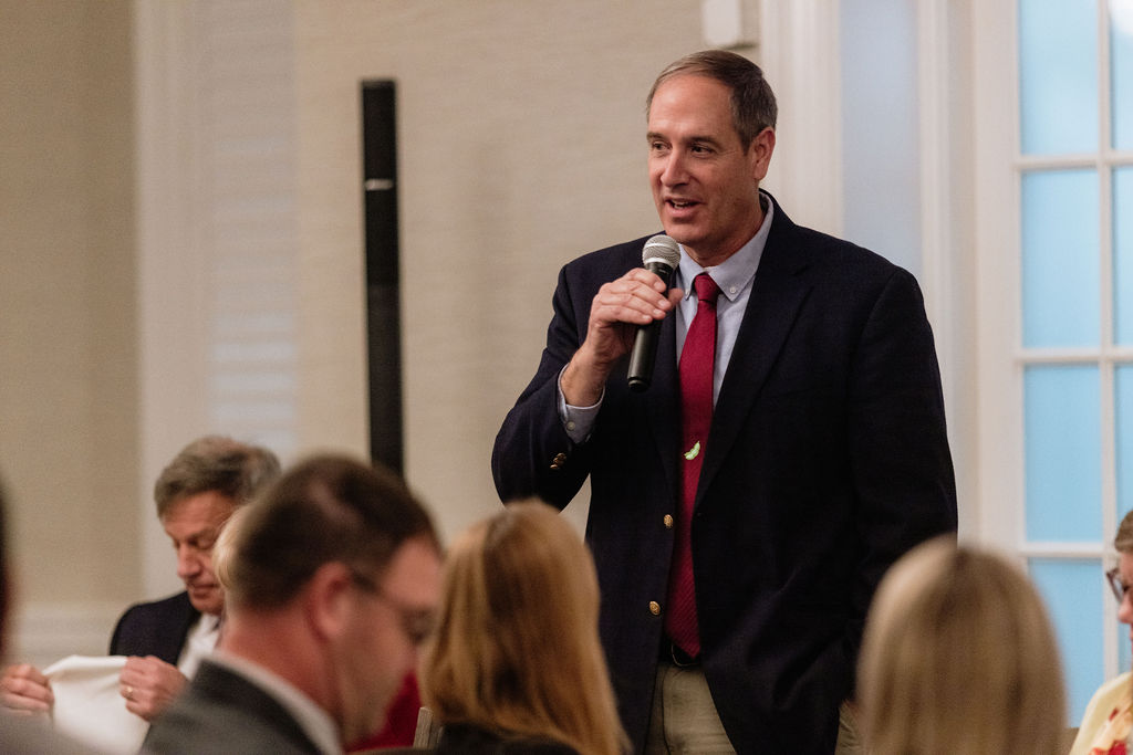 A man in a blue suit holds a microphone to address attendees on the first night of ASA/WISHH’s global food security dialogue in Annapolis, Maryland.