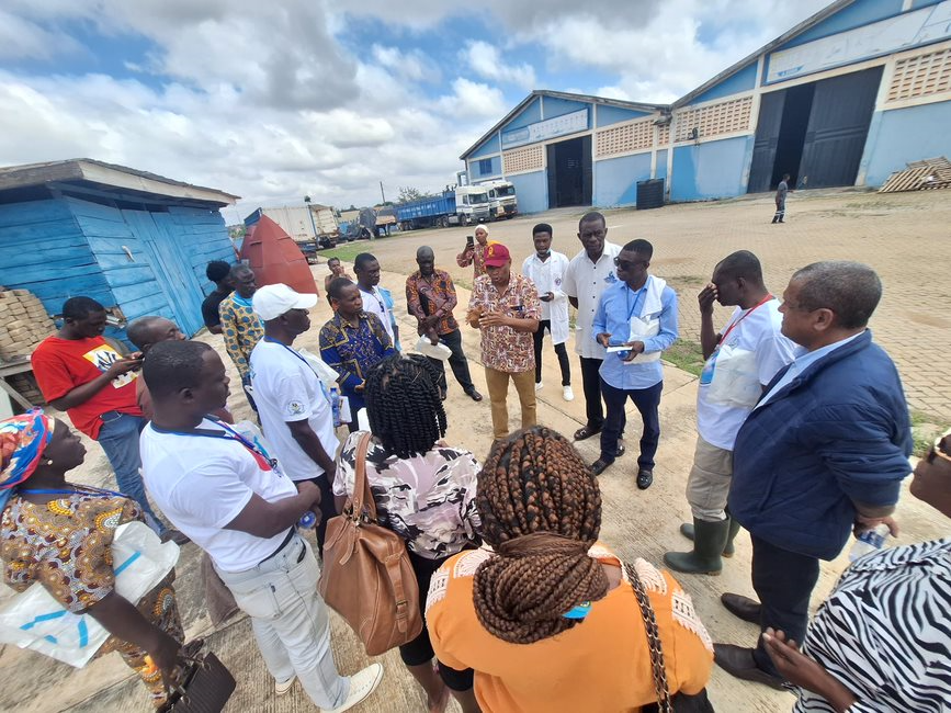 Group of Ghanaian egg producers listening to a man speaking during a visit to a farm.