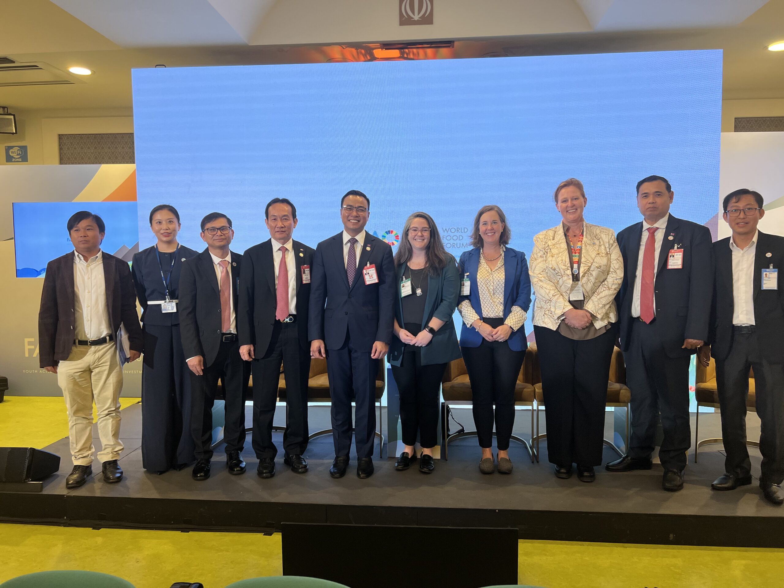 Ten people in business attire standing side by side in front of a screen with the World Food Forum logo.