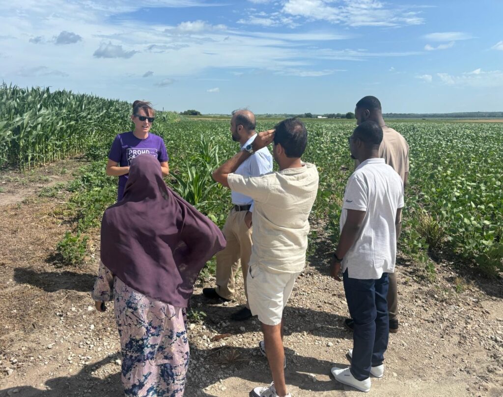 A farmer shows her soybeans and corn to a group of people.
