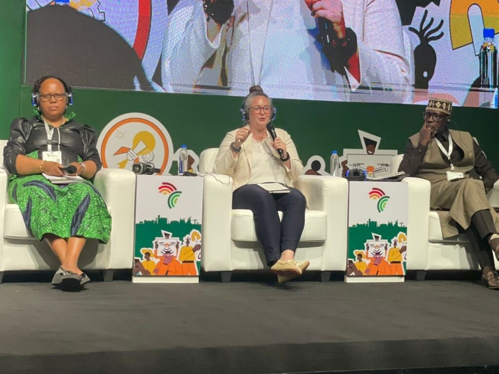 WISHH Executive Director Gena Perry sits between two other panelists on a stage.