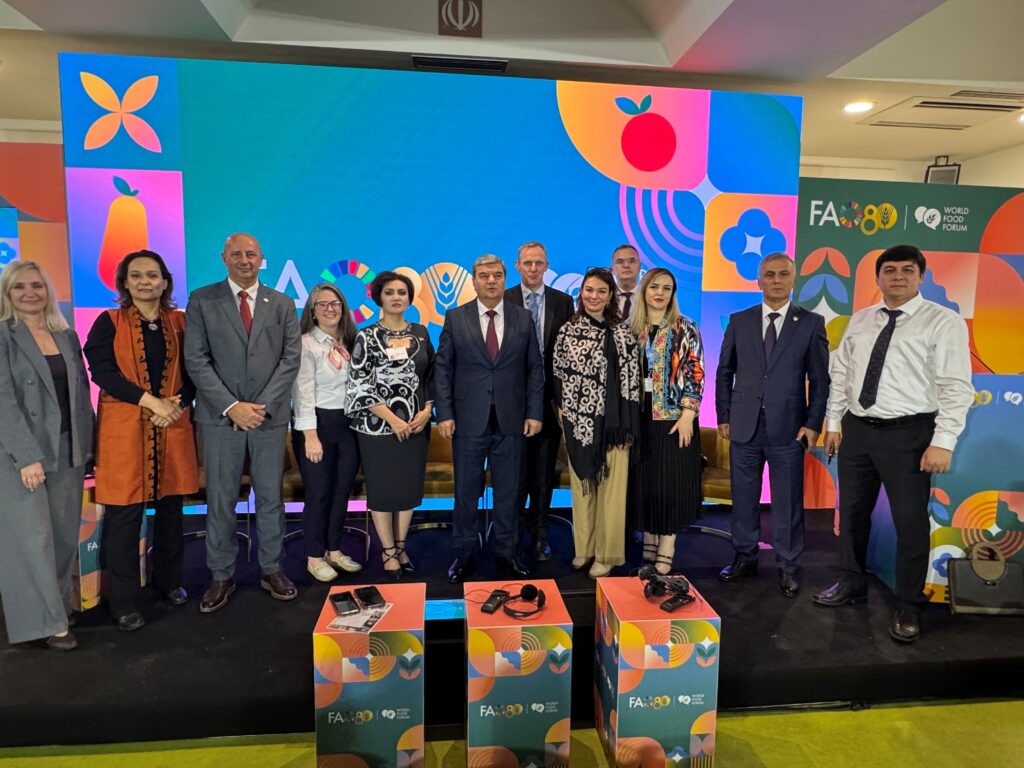 11 people dressed formally stand side by side as they pose for a photo.