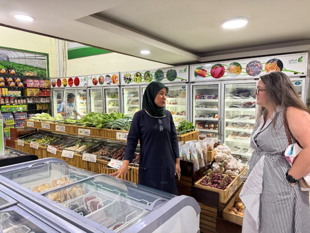 Two women standing and talking in a grocery store.