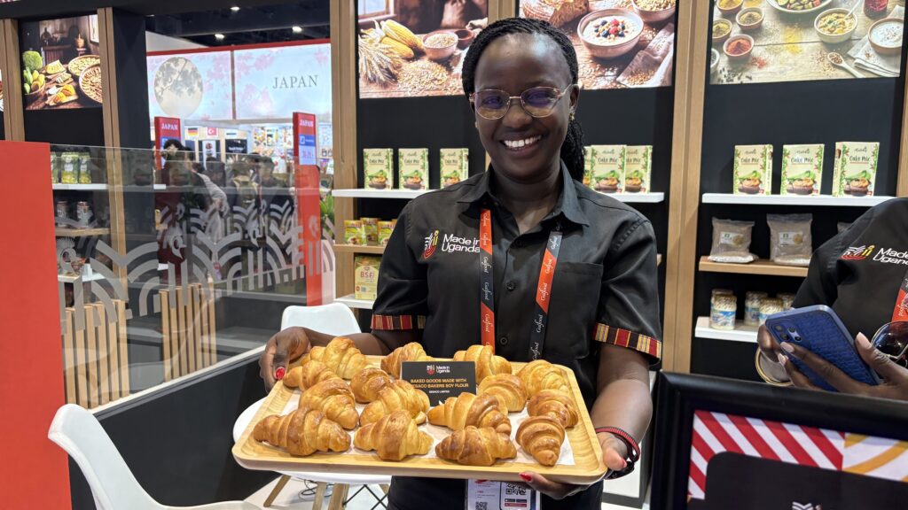 A woman holds a baking tray containing croissants.