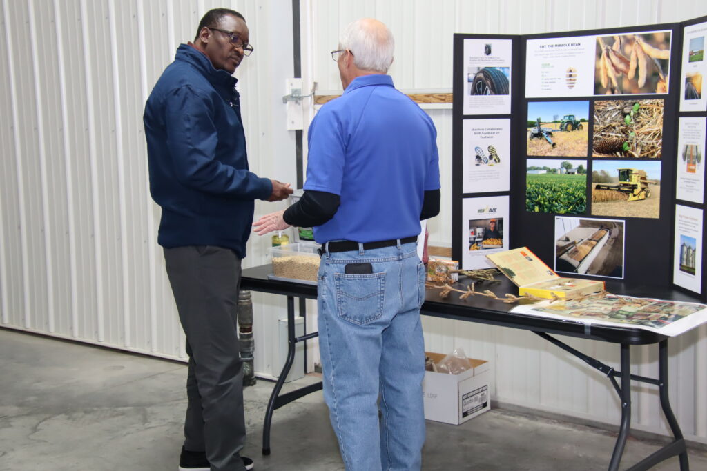 Two men talking in front of a table.