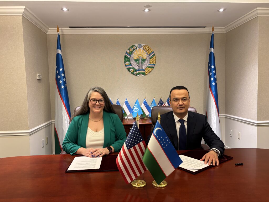 WISHH Executive Director Gena Perry sits next to an Uzbekistan government official behind a desk.