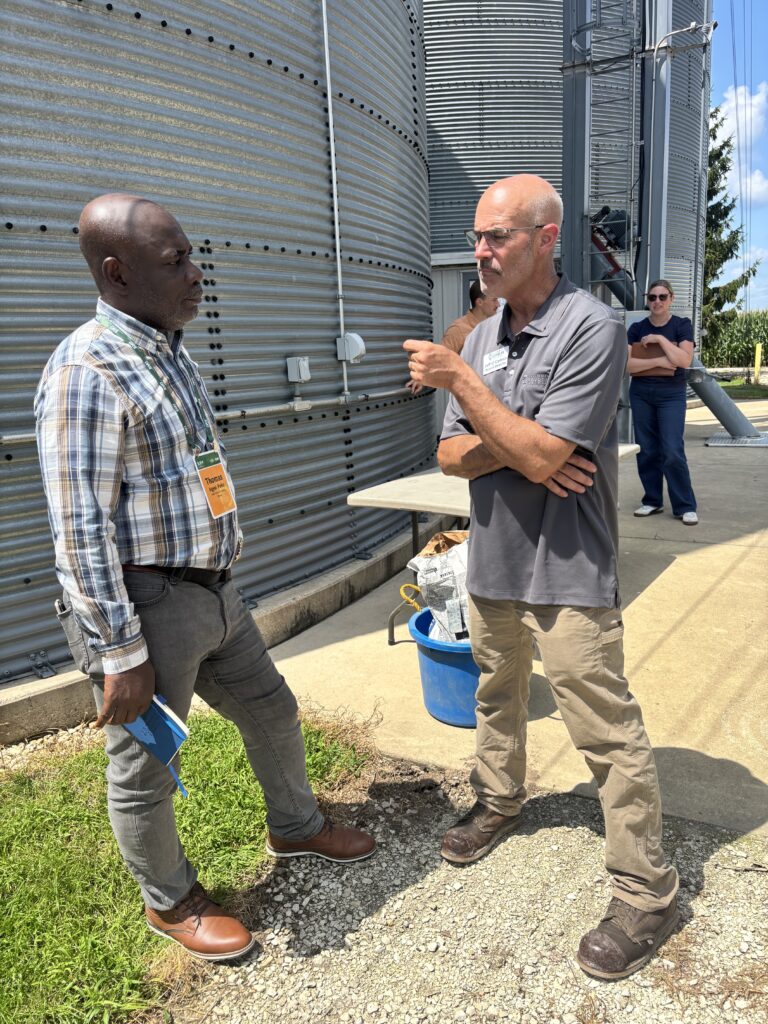Two men engaged in conversation on a farm.